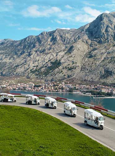 Five tuk tuks on a Boka bay tour, with Kotor old town behind.